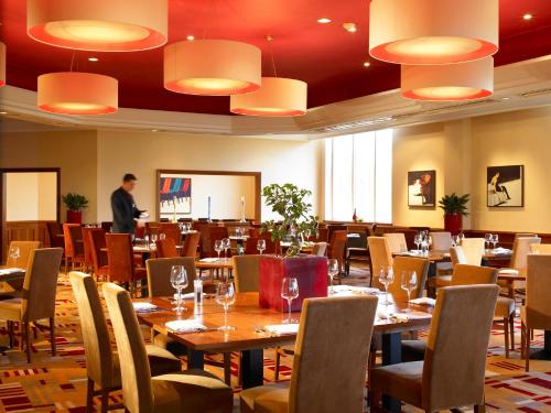 a restaurant with tables and chairs and a man standing in the background at Mercure Daventry Court Hotel in Daventry
