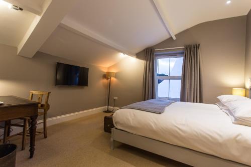 a bedroom with a bed and a desk and a window at The Redan Inn in Chilcompton
