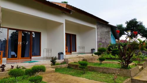 a white house with a garden in front of it at Embun Rinjani Homestay in Senaru