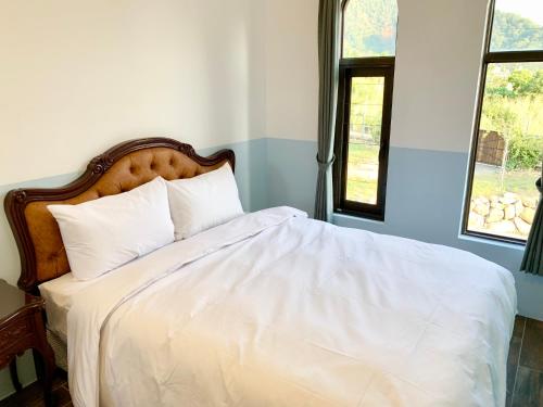 a bedroom with a white bed with two windows at Villa San Diego in Puli