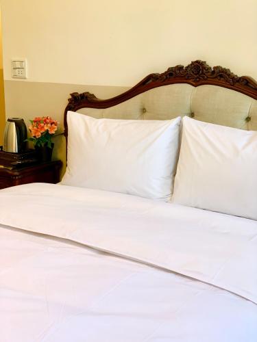 a bed with white pillows and a wooden headboard at Villa San Diego in Puli
