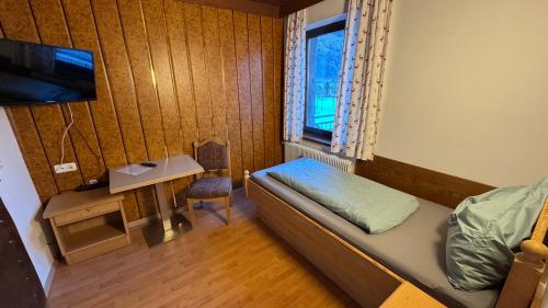 a small room with a bed and a table and a window at Botenwirt - Self Check in in Spital am Pyhrn