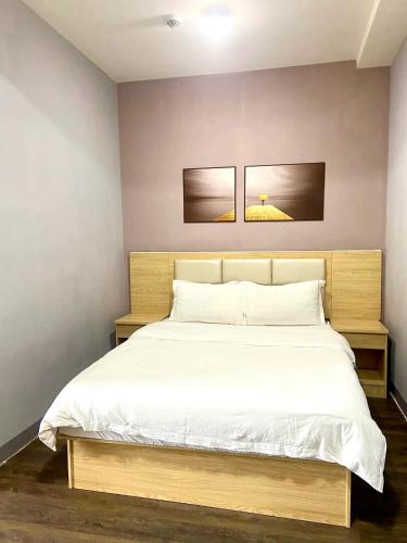 a bedroom with a white bed with two pictures on the wall at La Chicka Staycation in Coast Residences in Manila