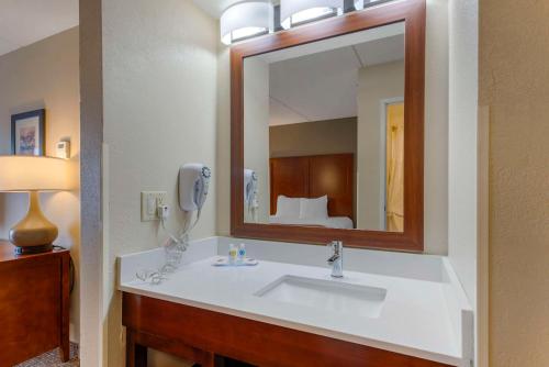 a bathroom with a sink and a mirror and a bed at Comfort Inn & Suites Wilkes Barre - Arena in Wilkes-Barre