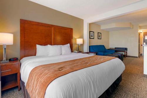 a hotel room with a large bed and a blue chair at Comfort Inn & Suites Wilkes Barre - Arena in Wilkes-Barre