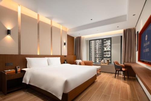 a hotel room with a large bed and a window at 滨江万璟酒店 One Gem Hotel in Haikou