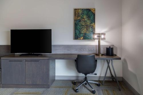 a desk with a television and a chair in a room at Hilton Garden Inn Fredericton in Fredericton