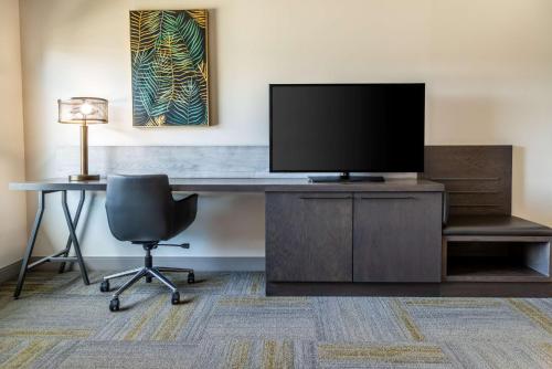 a desk with a television and a chair in a room at Hilton Garden Inn Fredericton in Fredericton