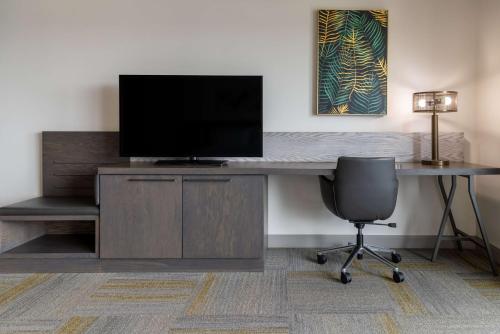 a desk with a television and a chair in a room at Hilton Garden Inn Fredericton in Fredericton