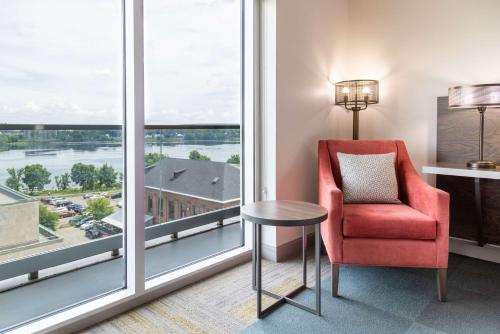 a room with a red chair and a large window at Hilton Garden Inn Fredericton in Fredericton