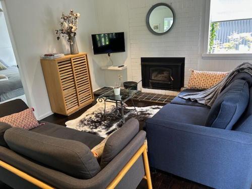 a living room with two blue couches and a fireplace at Maisie's Cottage in Mount Victoria