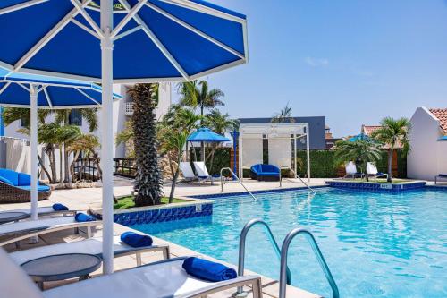 a swimming pool with chairs and umbrellas at TRYP by Wyndham Aruba in Palm-Eagle Beach