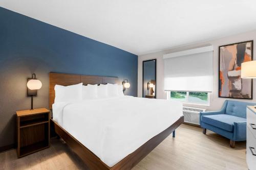 a bedroom with a large white bed and a blue wall at Everhome Suites Fayetteville near Fort Bragg in Fayetteville