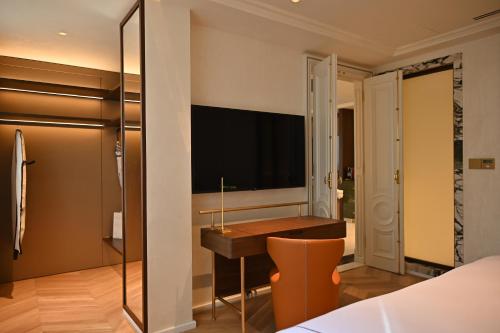a bedroom with a desk and a television on the wall at The Townhouse Hotel - Small Luxury Hotels of the World in Islamabad