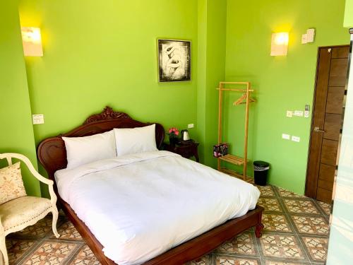 a green bedroom with a bed and a chair at Villa San Diego in Puli