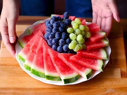 a plate of watermelon and fruit on a table at Hoi An Tháng 1 Villa in Hoi An