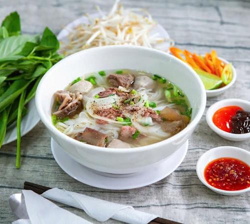 a bowl of soup on a table with other foods at Hoi An Tháng 1 Villa in Hoi An