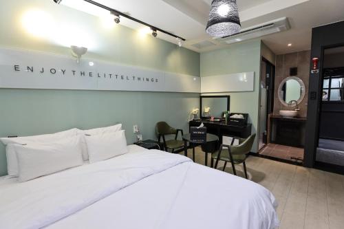 a bedroom with a bed and a desk and a bathroom at Hotel Kkuljam Stay in Jinju