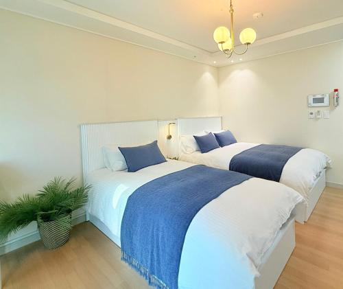 two beds with blue and white sheets in a bedroom at Mango&Haru House in Seoul