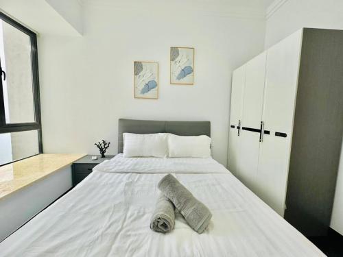 a bedroom with a white bed with a towel on it at R&F Seine Region in Johor Bahru