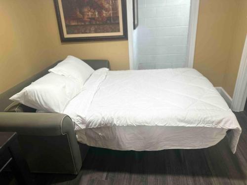 a bed with white sheets and pillows in a room at Spacious Basement Apartment near metro downtown Washington DC in Capitol Heights