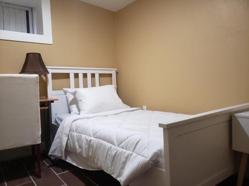 a bedroom with a bed with white sheets and a lamp at Spacious Basement Apartment near metro downtown Washington DC in Capitol Heights