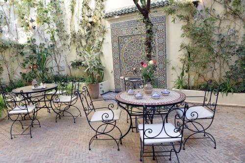 a patio with tables and chairs in a garden at Riad Jardin Chrifa in Fès
