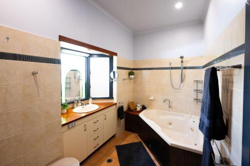 a bathroom with a tub and a sink and a bath tub at Heavenly Palms on Collinson in Westcourt