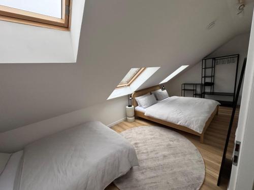 a attic bedroom with two beds and a rug at ApartNaest Radeberg - vollausgestattete 1 - 4 Zimmer Apartments I 24h flexibler mobiler Check-in via Link I Parkplatz auf Anfrage I Platz für bis zu 60 Personen in Radeberg