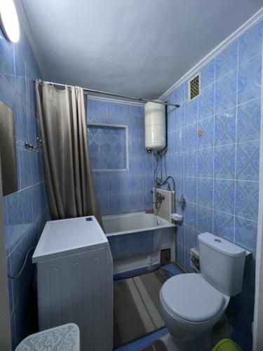 Un baño con azulejos azules, inodoro y bañera. en Bayir Studio Apartment, en Karakol