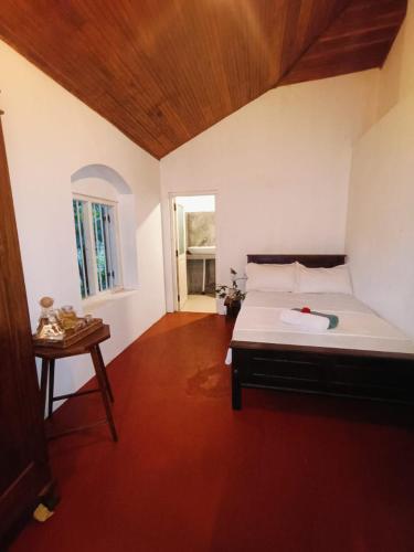 a bedroom with a bed and a table and a window at Lekham Walauwa in Matale