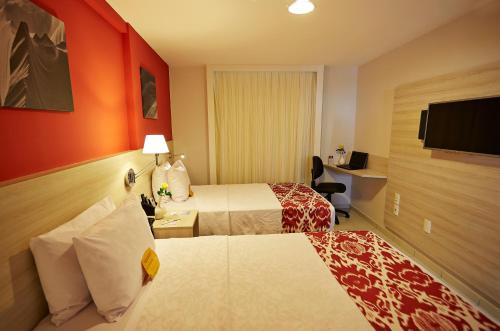 a hotel room with two beds and a flat screen tv at Comfort Hotel & Suites Natal in Natal