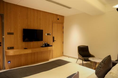 a room with a bed and a television and a chair at RAGA - A Boutique Hotel in Belgaum