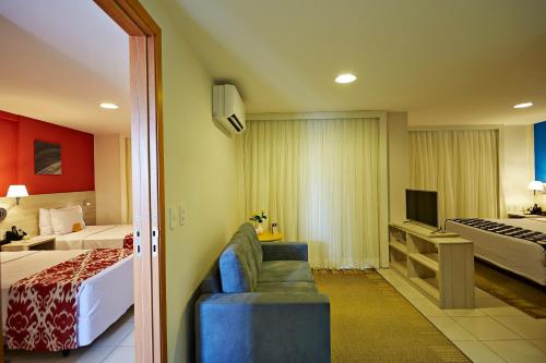a hotel room with a bed and a couch and a television at Comfort Hotel & Suites Natal in Natal