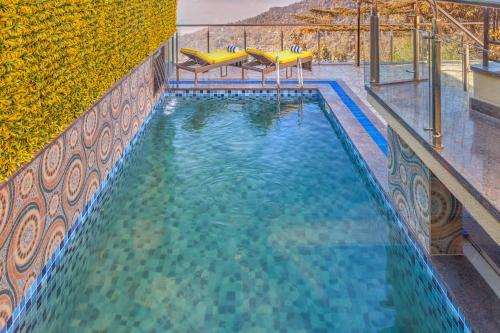 a swimming pool with blue water and yellow tables at WelcomHeritage Natraj, Mcleod Ganj in McLeod Ganj