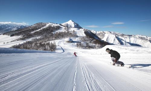 two people are skiing down a snow covered mountain at BBQ 夏季プール マッサージチェア 舞子スノーリゾート 加賀屋旅館 南魚沼 Kagaya Ryokan 加贺屋旅馆 in Minami Uonuma