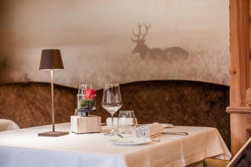a table with wine glasses and a deer in the background at Cerana Relax Hotel in Madonna di Campiglio