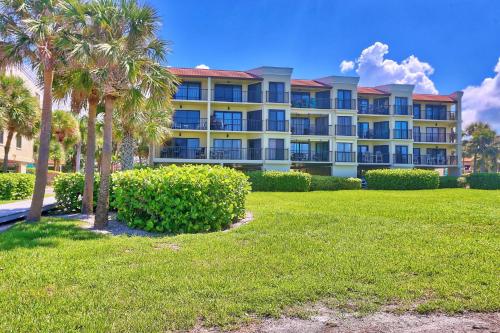 a large apartment building with palm trees in a park at Land's End 11-203 Beach Front - Premier in St Pete Beach