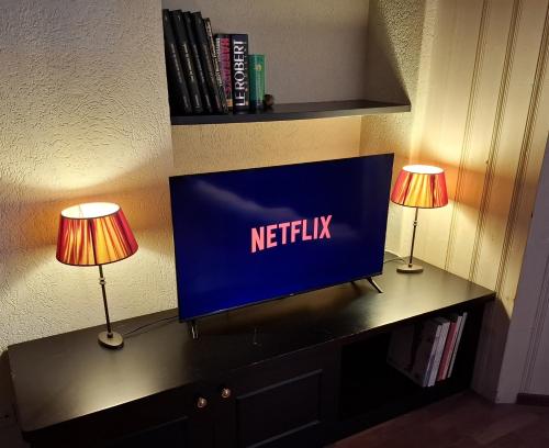 a television on a desk with two lamps on it at Le Nid d'aigle apt Leysin centre avec forfait piscine sauna jacuzzi en option in Leysin