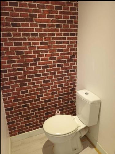 - des toilettes blanches devant un mur de briques dans l'établissement Appart no2 motte T3 Secure Parking, à Tourcoing