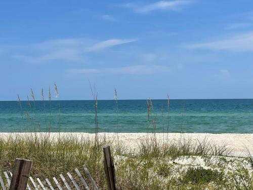 a beach with chairs and the ocean in the background at 1st to the Beach-Sunset Beach-Beachfront-Pet Friendly-Hot Tub in St. George Island