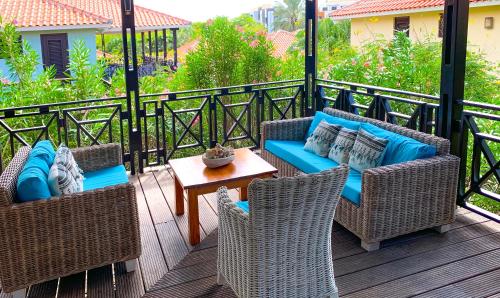 a patio with wicker chairs and a table on a deck at Vrijstaande BB BEACH Villa Azure in Blue Bay
