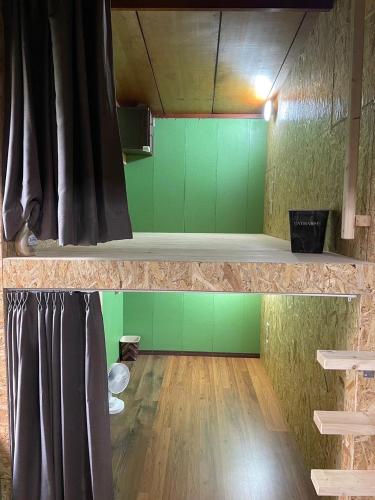 a room with green walls and a stage at ゲストハウス潮目 in Shibetsu