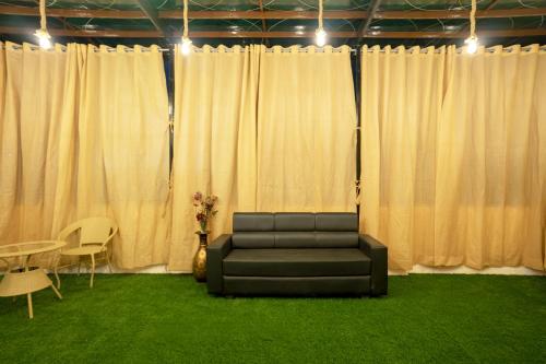 a couch sitting in a room with white curtains at The Lavish Affair in Bhuj