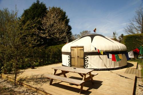 a yurt with a wooden picnic table and a bench at Dogwood Yurt in Rye