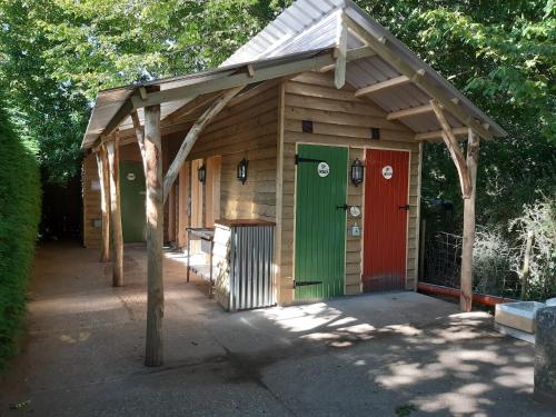 a wooden shed with a green and red door at Dogwood Yurt in Rye