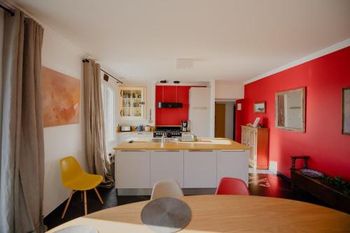 une cuisine avec des murs rouges et une table et des chaises dans l'établissement La Ronce, à Châteauneuf-sur-Loire