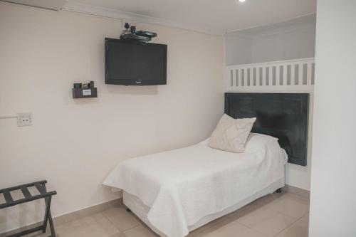 a bedroom with a bed and a tv on the wall at Beside Still Waters Boutique Hotel in Durban