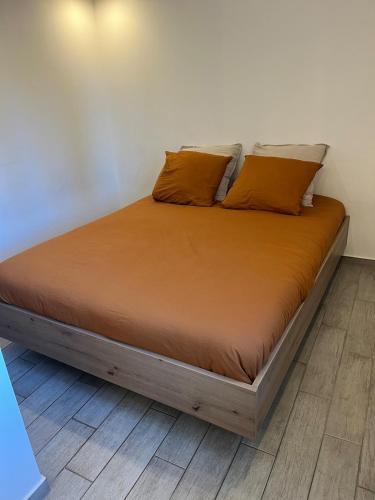 - un lit avec des draps et des oreillers orange dans l'établissement Le Nid ideal, au Muy