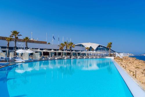 a large swimming pool next to a beach with palm trees at Side Sea View B, Steps Away to Bugibba Jetty, For the Blue Lagoon Boats and Other Islands in St Paul's Bay